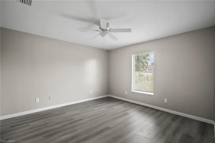 Empty room with ceiling fan and dark wood-type flooring