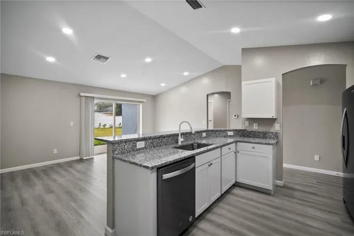 Kitchen with stainless steel appliances, white cabinetry, hardwood / wood-style flooring, and sink