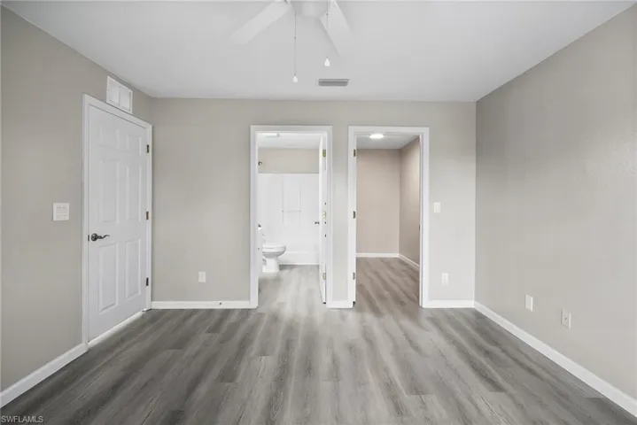 Unfurnished bedroom with ensuite bathroom, hardwood / wood-style floors, and ceiling fan