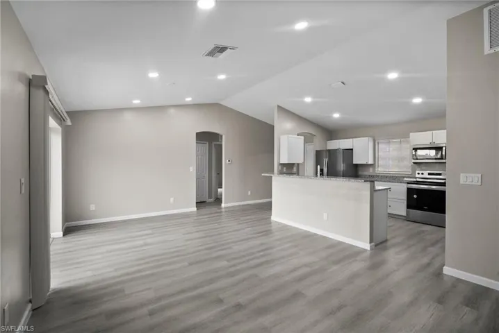 Kitchen featuring light hardwood / wood-style floors, white cabinetry, lofted ceiling, and appliances with stainless steel finishes