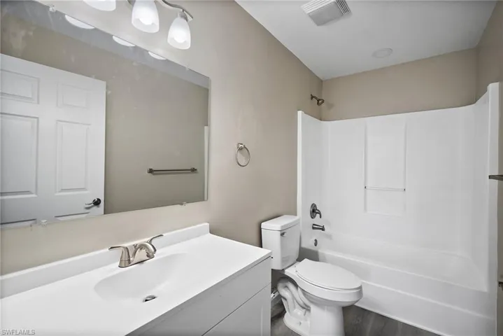 Full bathroom with shower / bathing tub combination, wood-type flooring, vanity, and toilet