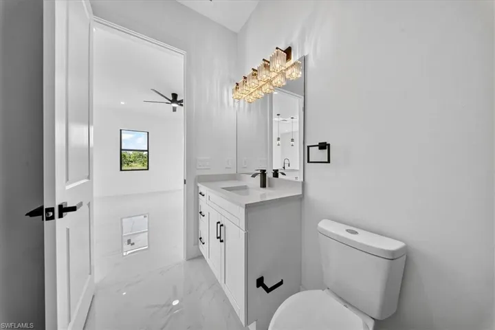 Bathroom featuring light marble finish flooring, vanity, and ceiling fan