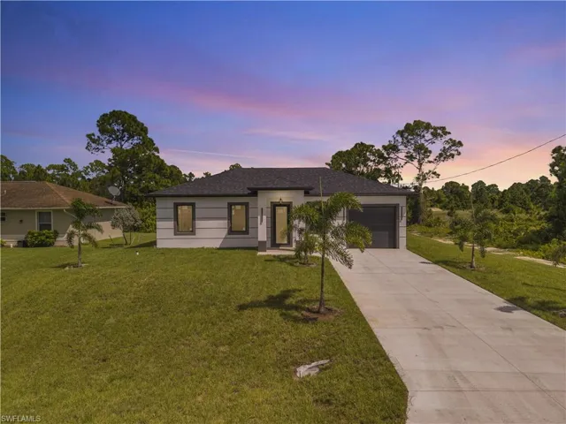 Ranch-style house with a lawn, concrete driveway, an attached garage, and roof with shingles