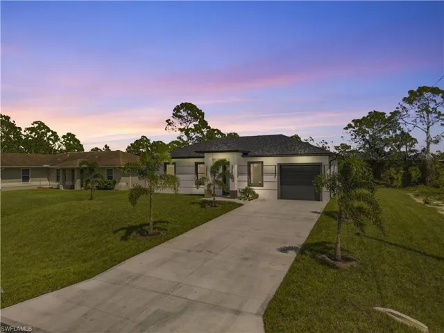 View of front of house featuring driveway, a garage, a lawn, and stucco siding