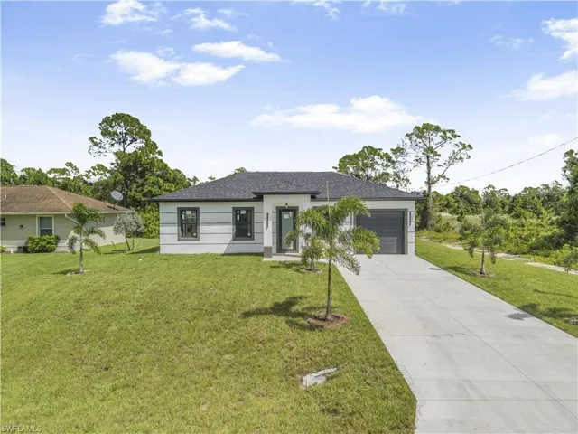 View of front of property with driveway, a front yard, an attached garage, and roof with shingles
