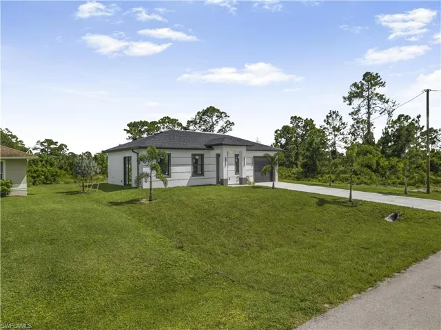 View of front of house featuring driveway, a front yard, and a garage