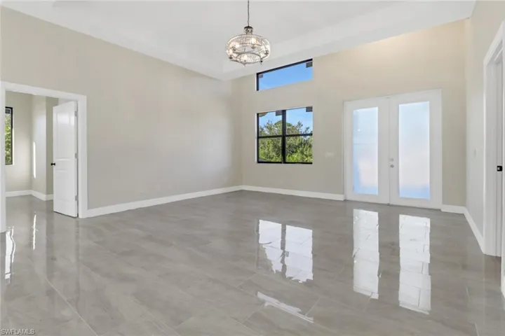 Spare room with french doors and a notable chandelier