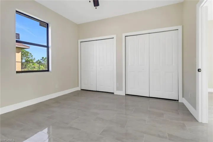 Unfurnished bedroom featuring two closets, ceiling fan, and light tile patterned flooring