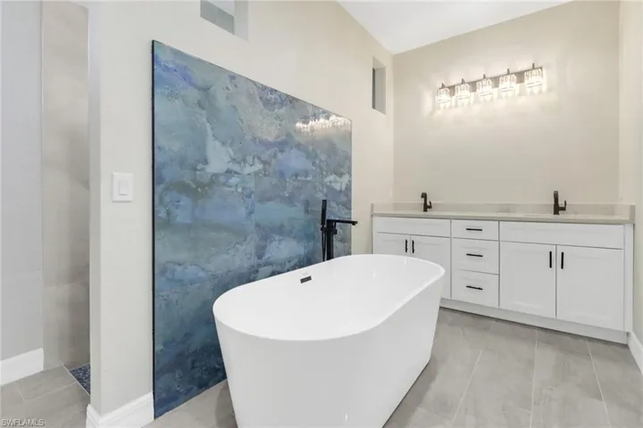 Bathroom with a washtub, vanity, tile patterned floors, and tile walls