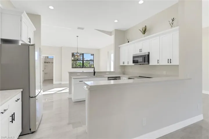 Kitchen featuring white cabinets, kitchen peninsula, sink, and appliances with stainless steel finishes