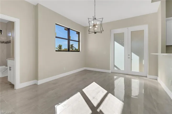 Spare room featuring an inviting chandelier and french doors