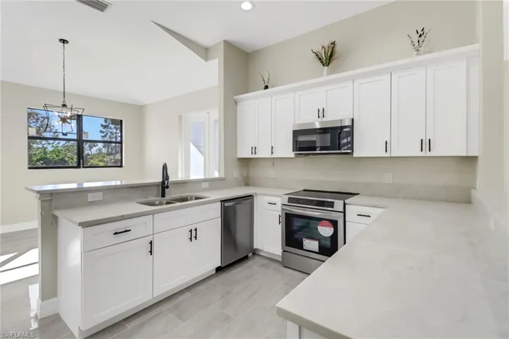 Kitchen with kitchen peninsula, pendant lighting, stainless steel appliances, and sink