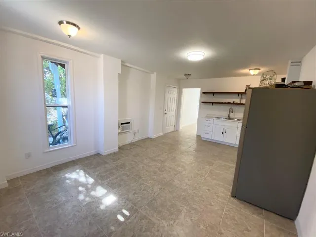 Kitchen with white range oven, exhaust hood, sink, refrigerator, and light tile floors