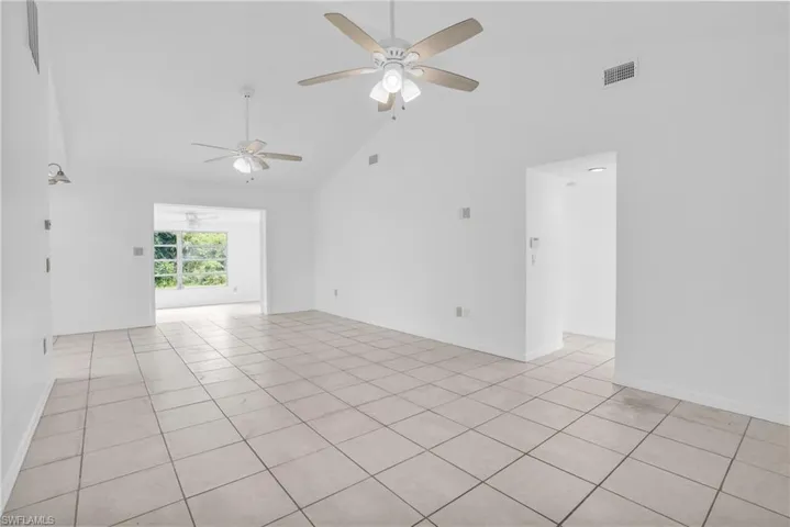 Spare room with light tile patterned floors, ceiling fan, and high vaulted ceiling