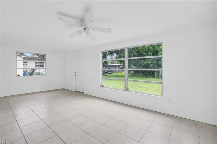 Empty room with light tile patterned floors and ceiling fan