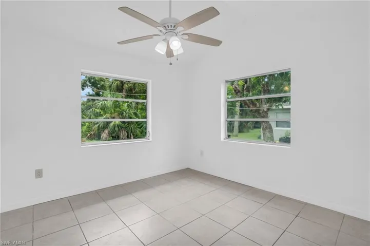Tiled empty room featuring a healthy amount of sunlight, ceiling fan, and lofted ceiling