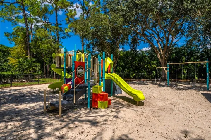Communal playground featuring fence and view of scattered trees