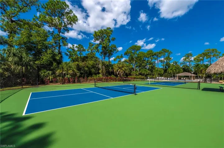View of tennis court with community basketball court and fence