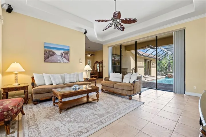 Living area featuring a ceiling fan, a tray ceiling, baseboards, and crown molding