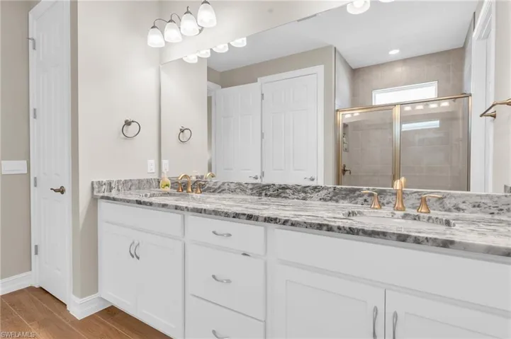 Bathroom featuring a shower with door, vanity, and wood-type flooring