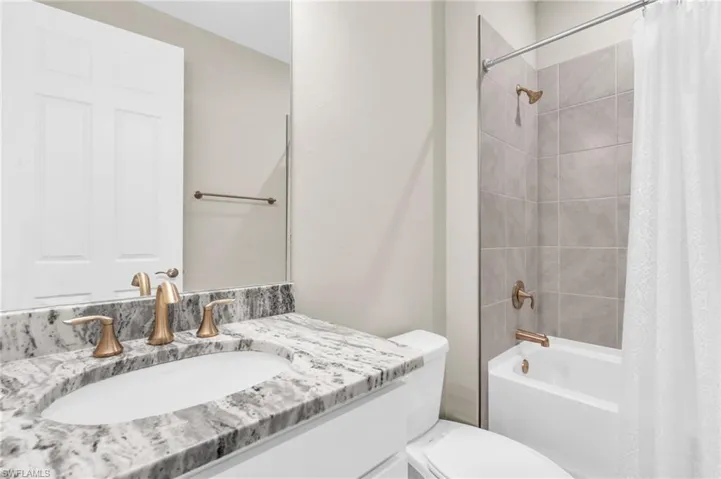 Full bathroom with vanity, toilet, and shower / bath combination with curtain