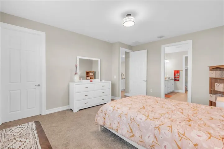 Bedroom with connected bathroom and light carpet