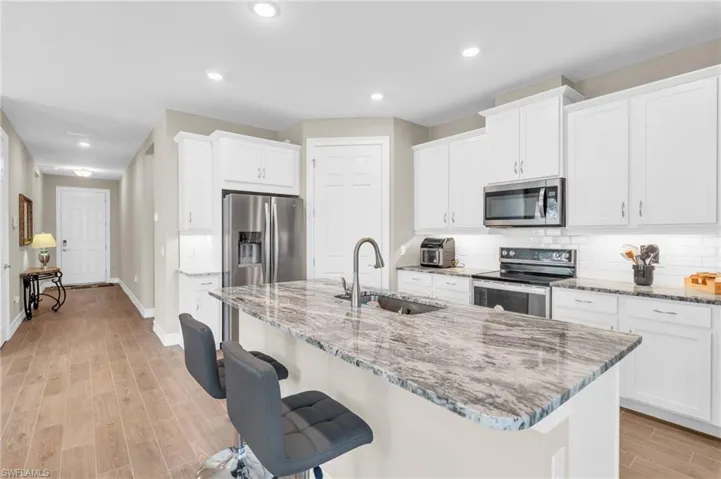 Kitchen featuring a center island with sink, sink, white cabinetry, and stainless steel appliances