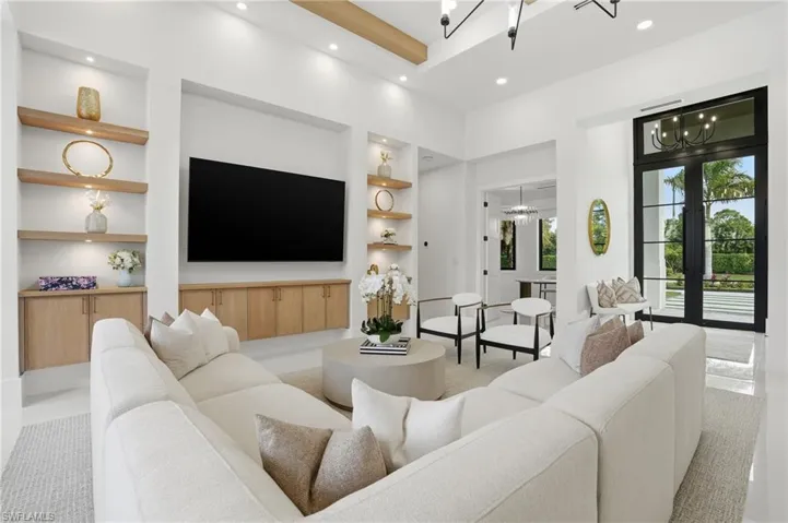 Living area with built in shelves, a chandelier, recessed lighting, a towering ceiling, and french doors