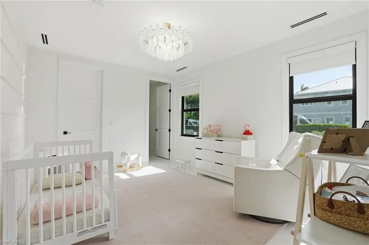 Bedroom with a crib, a chandelier, and carpet
