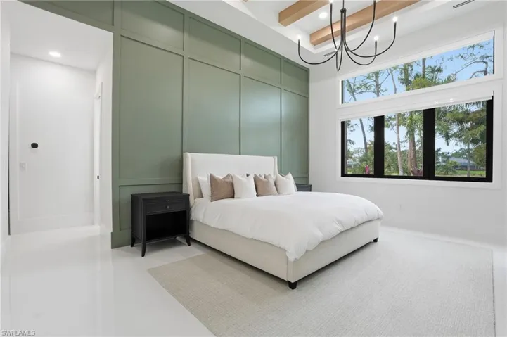 Bedroom with recessed lighting, a chandelier, a decorative wall, and beamed ceiling