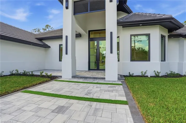 Doorway to property with a tiled roof, a yard, stucco siding, and french doors