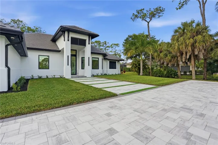 View of front of home with a front lawn, a tile roof, and stucco siding