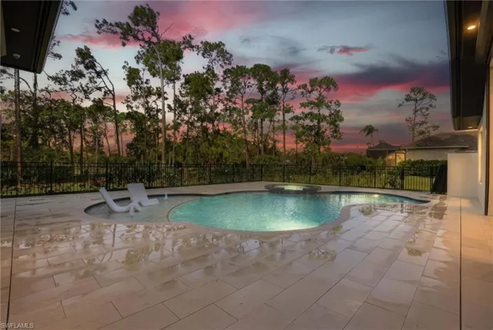 Pool at dusk featuring a patio area and a pool with connected hot tub