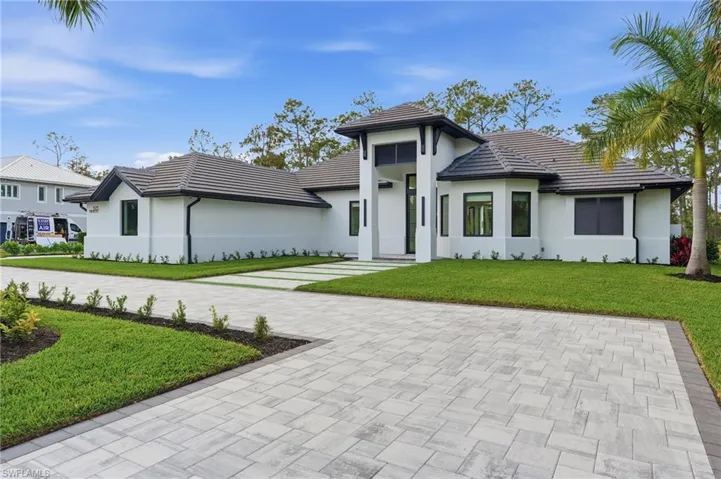 View of front of home featuring a front lawn, stucco siding, and a tile roof