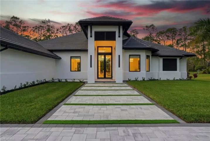 Property entrance with a tiled roof, stucco siding, a yard, and french doors