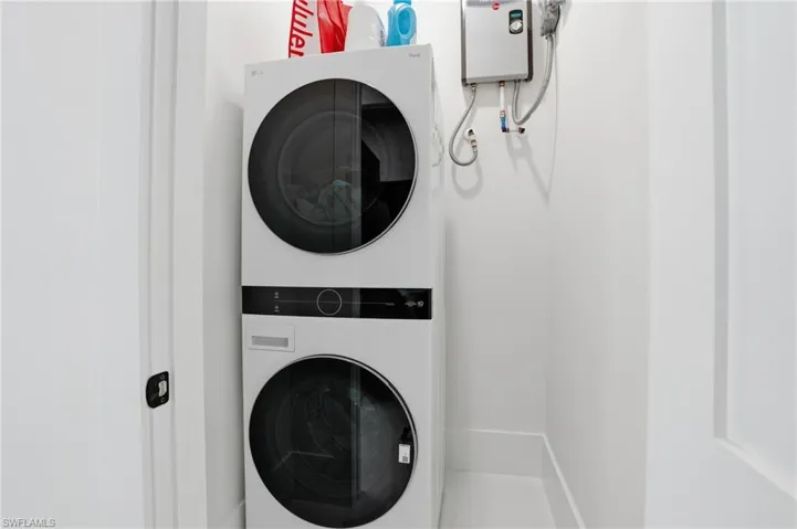 Washroom featuring stacked washing machine and dryer and water heater