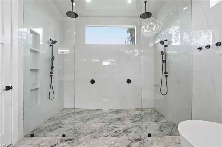 Bathroom with marble tiled flooring, a marble finish shower, and a freestanding tub