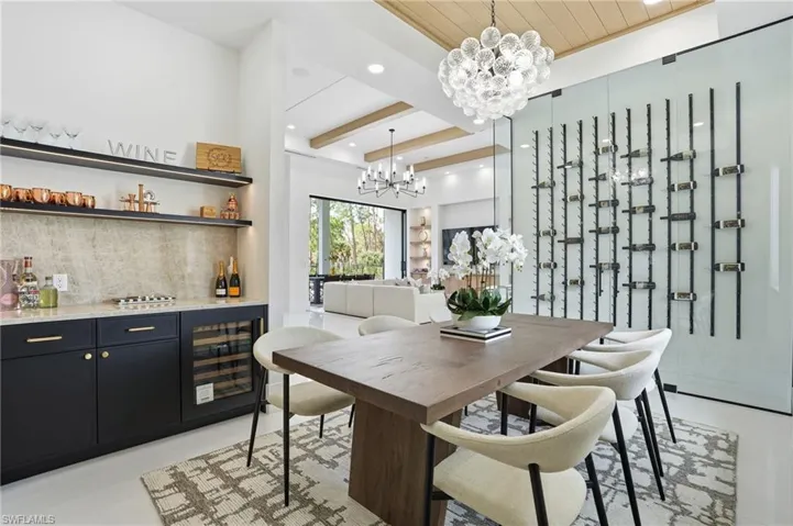 Dining space with beamed ceiling, recessed lighting, beverage cooler, a chandelier, and bar area