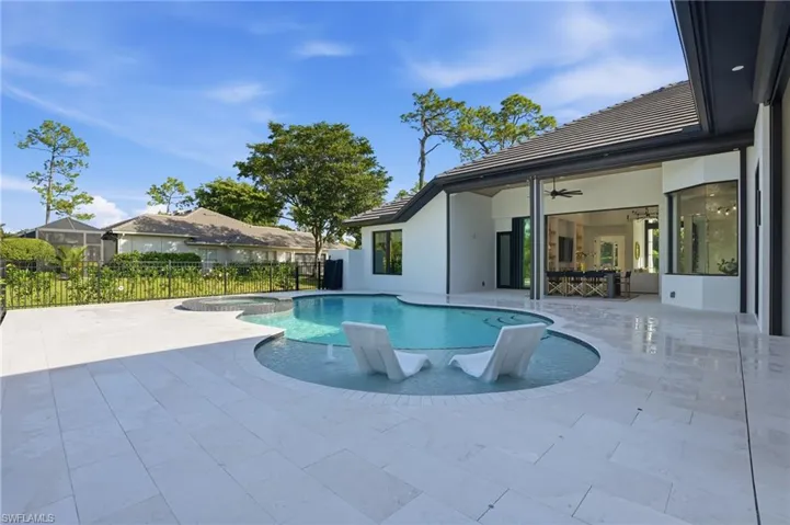 View of pool with a patio and a pool with connected hot tub