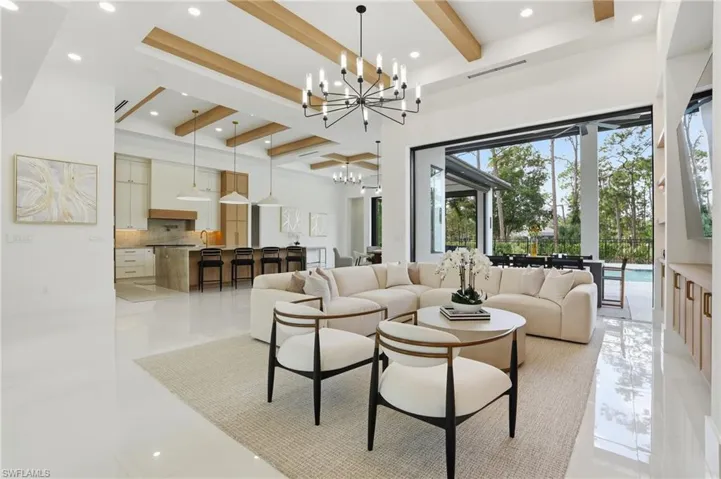 Living area with beam ceiling, recessed lighting, a high ceiling, and a chandelier