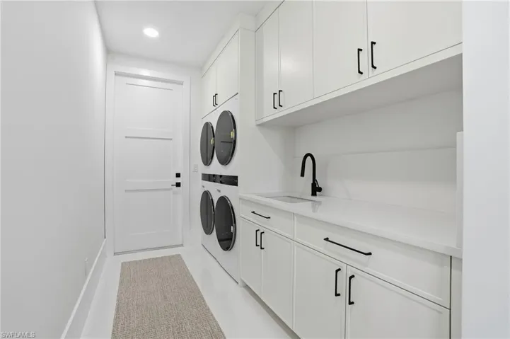Washroom featuring cabinet space, estacked washer and dryer, and recessed lighting