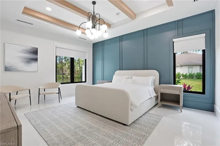 Bedroom featuring a chandelier, a decorative wall, and beam ceiling