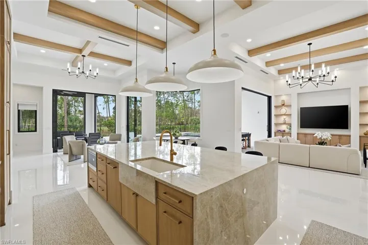 Kitchen with a chandelier, open floor plan, light stone countertops, beam ceiling, and recessed lighting