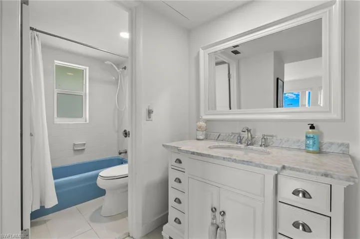 Full bathroom with shower / bath combo with shower curtain, vanity, tile patterned floors, and toilet