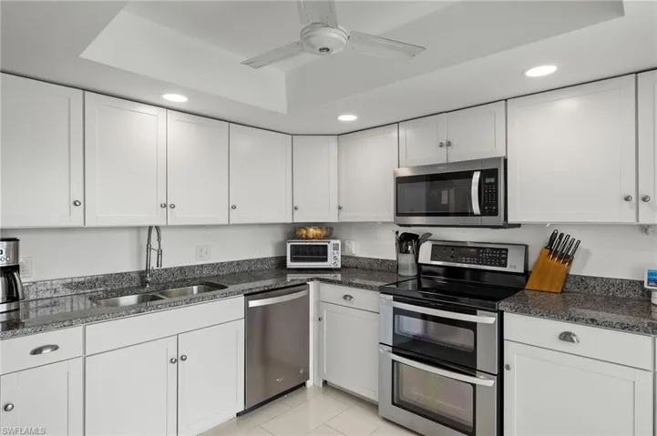 Kitchen featuring white cabinets, stainless steel appliances, sink, and ceiling fan