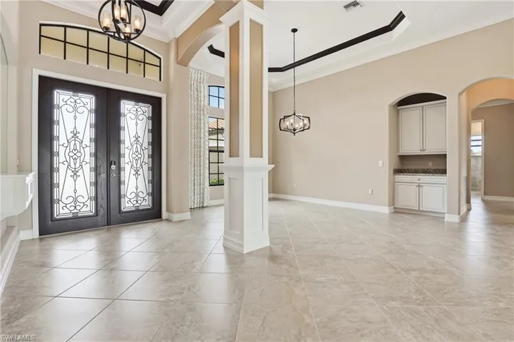 Foyer featuring a chandelier, french doors, ornamental molding, arched walkways, and a towering ceiling