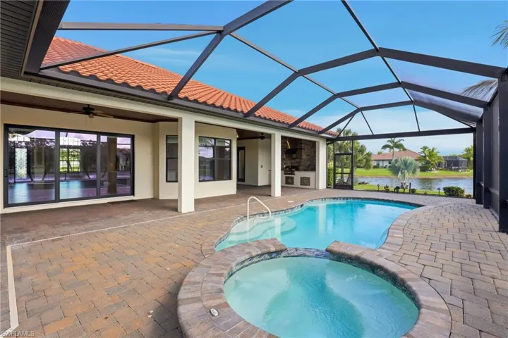 View of swimming pool featuring a sunroom, a pool with connected hot tub, a patio area, a lanai, and a water view