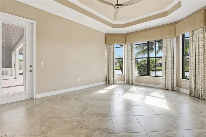 Unfurnished room featuring ornamental molding, a tray ceiling, plenty of natural light, and ceiling fan