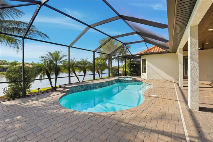 View of pool with a sunroom, a patio area, a lanai, a pool with connected hot tub, and a water view