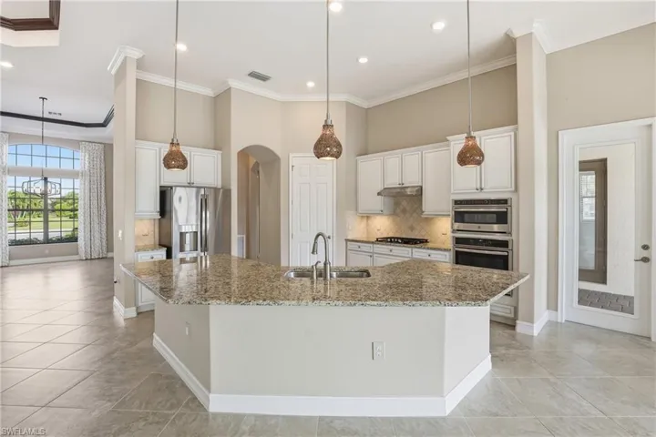 Kitchen featuring backsplash, white cabinets, pendant lighting, crown molding, and recessed lighting
